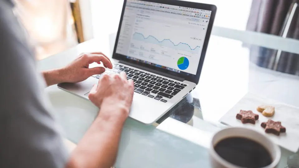 Pessoa analisando gráficos de resultados de anúncios em um notebook