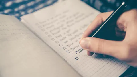 Mão escrevendo uma lista de tarefas em um caderno